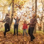 Family plays in autumn leaves
