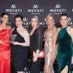 Actresses in formal dress posing with award
