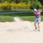 Golfer makes shot from sand trap